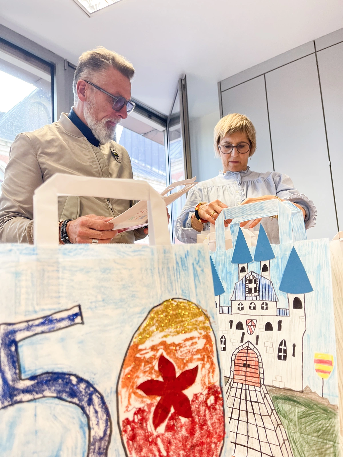 Personen schauen sich kunstvolle Tüten an