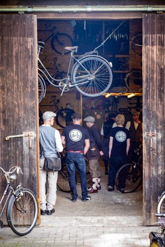 Fachsimpeln in Heikos Fahrradwerkstatt: Tweed Runner mit Schiebermütze und Knickerbockern bestaunen die historischen Räder an Wänden und Decke