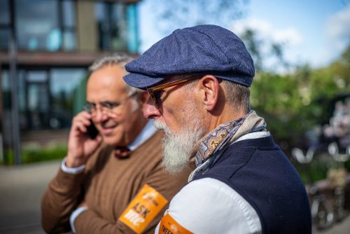 Kurzes Telefonat vor dem Start: zwei Tweed Run Organisatoren mit Schiebermütze am Treffpunkt Krantine