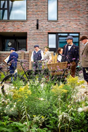 Tweed-Run-Teilnehmer mit Lastenrad zwischen blühenden Stauden am Hafen