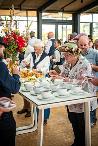 Am Tee-Buffet bedienen sich die Tweed Runner mit Tee und Scones, vorne eine Dame mit Blumenhut